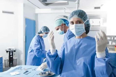 A team of medical professionals in surgical attire gathered in a well-equipped operating room, ready for a procedure.